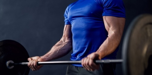a man in a blue shirt is holding a barbell