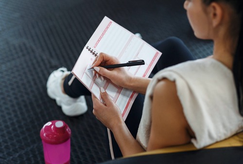 a young lady writing in a fitness planner