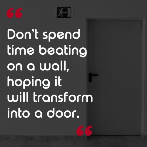 Inspirational quote about transformation and walls becoming doors with an image of a dark room and exit sign.