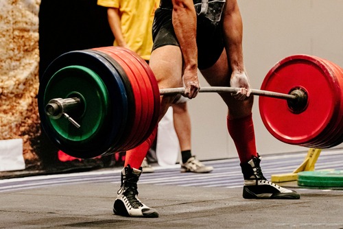 A competitive powerlifter performs a heavy deadlift with a loaded barbell at a weightlifting competition.