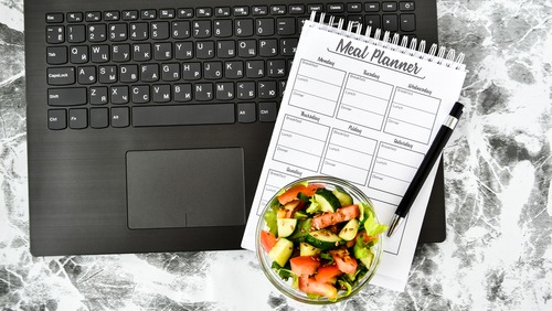 a notebook with a salad on a marble table