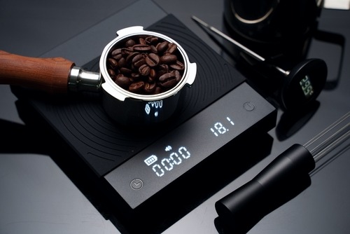a coffee grinder with coffee beans on a scale
