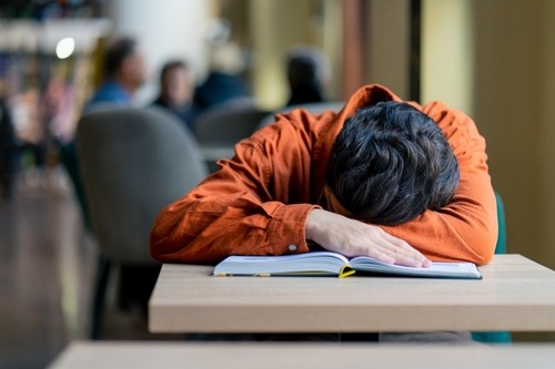 a man is sleeping on a desk in a library