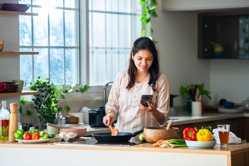 a woman is cooking in a kitchen with a phone