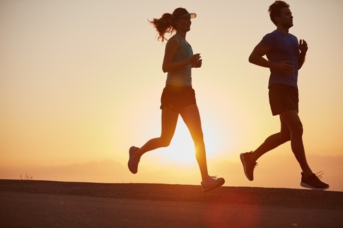 a man and woman jogging in the sun