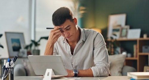 a man sitting at a desk with a laptop and a pen