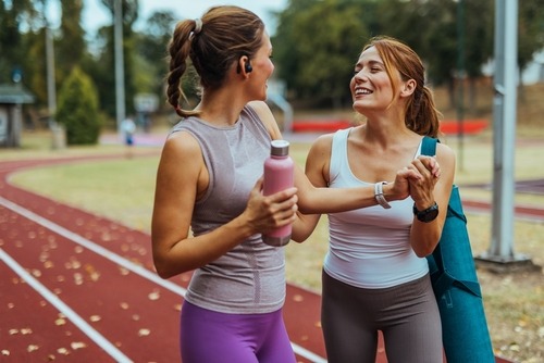 two women in sports wear standing on a track