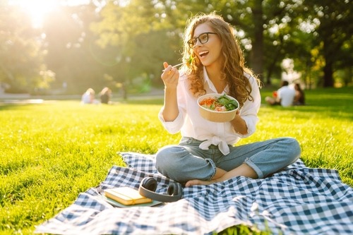 a woman sitting on a blanket in the grass