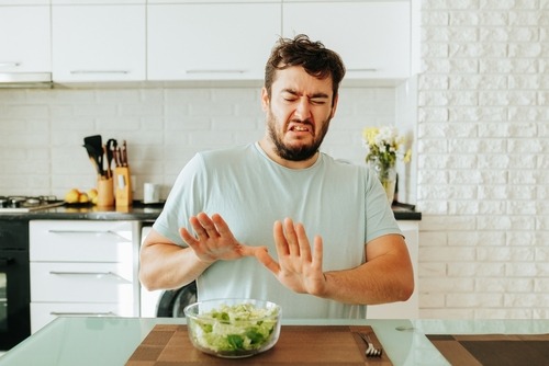 a man with a bowl of salad on a cutting board
