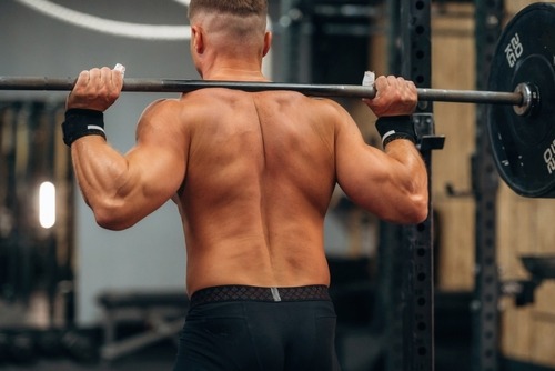 a man with a barbell in his hand on his back