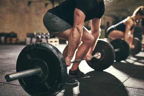 A man performing a heavy barbell deadlift during a strength training workout at a gym.