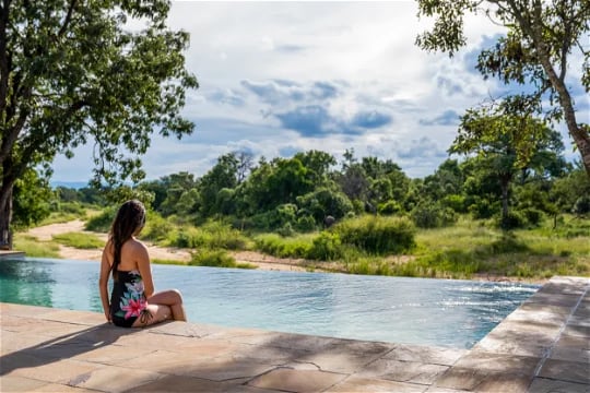 Guest enjoying luxury lodge pool overlooking Big Five game reserve.