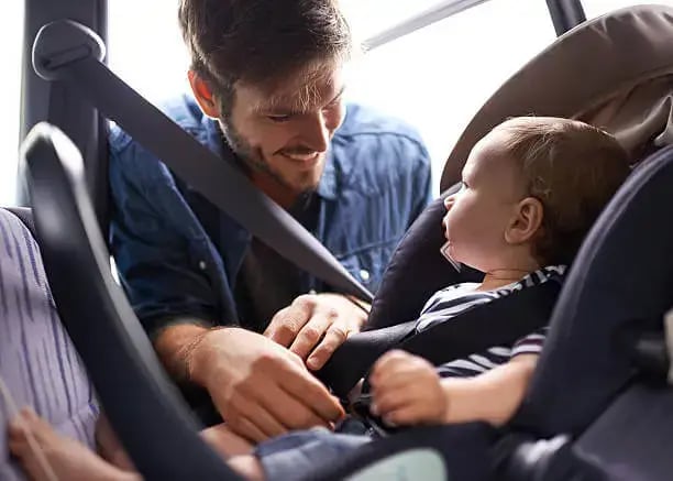 a man and a baby in a car seat