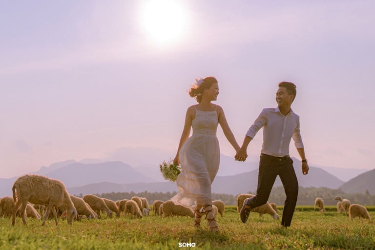 a man and woman holding hands while walking through a field
