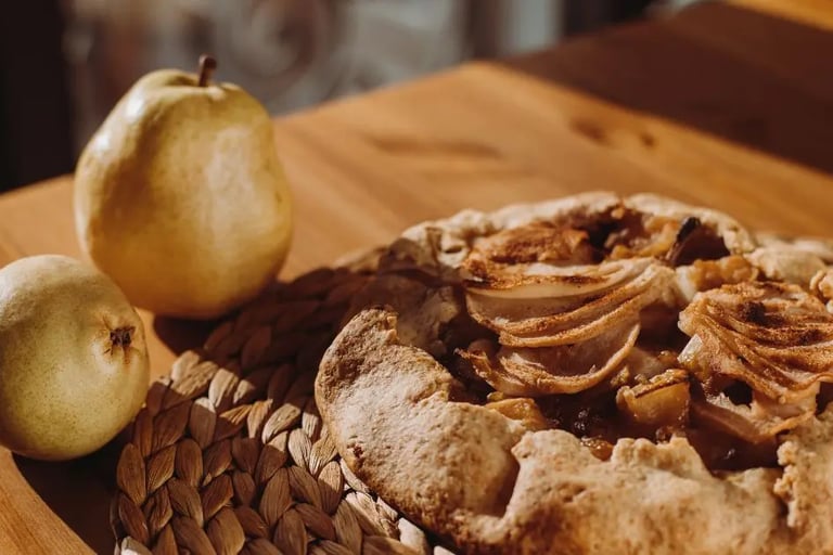 pear galette on a wooden table beside two fresh pears