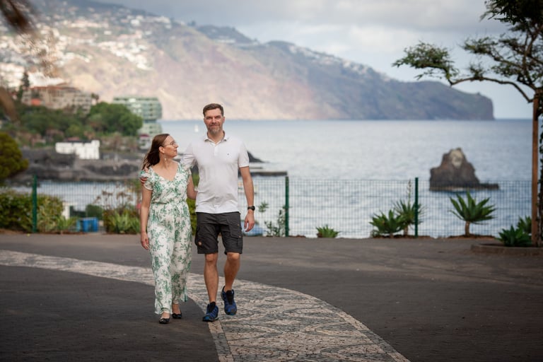 Couple walks along Funchal Lido Promenade, Madeira, with Atlantic coast and scenic cliffs in the background, lifestyle mood.