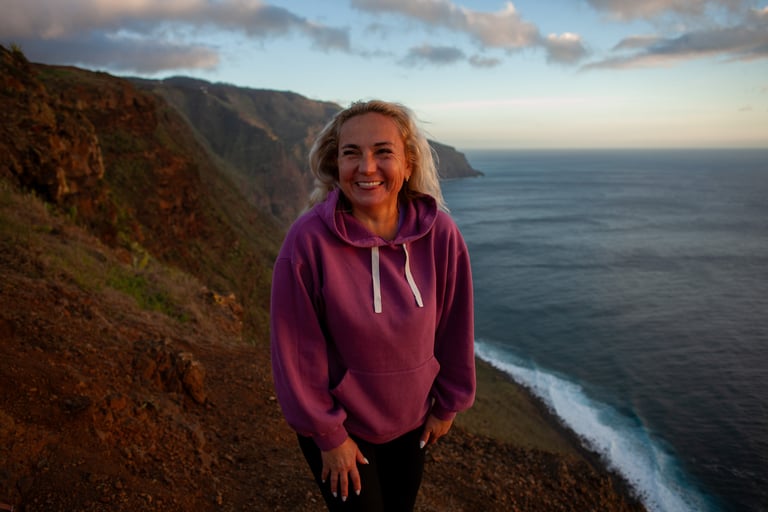 Woman in purple hoodie at dramatic Madeira sunset location