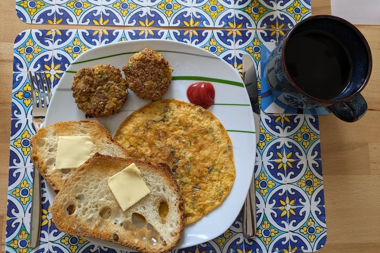 An Indian Omelet with toasted bread with butter and veg cutlet with some ketchup and a cup of coffee