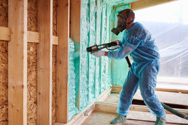 Worker spraying blue foam insulation