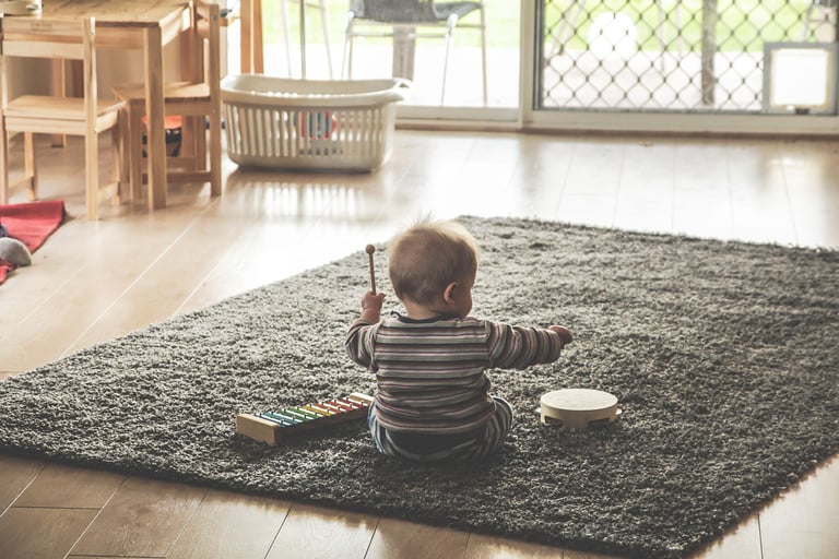 toddler playing with his toys on a grey rug