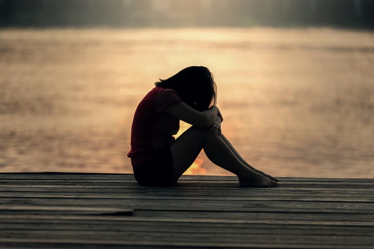 una mujer sentada en un muelle con actitud deprimida