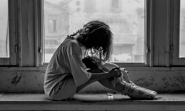 Adolescente sentada con cuerpo inclinado con actitud triste