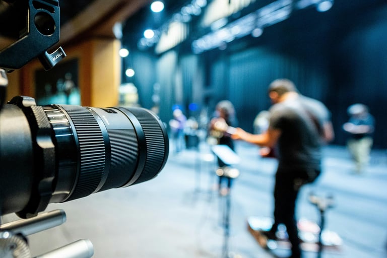 Professional cinema camera lens filming a live band performance on a professional stage with stage lighting.