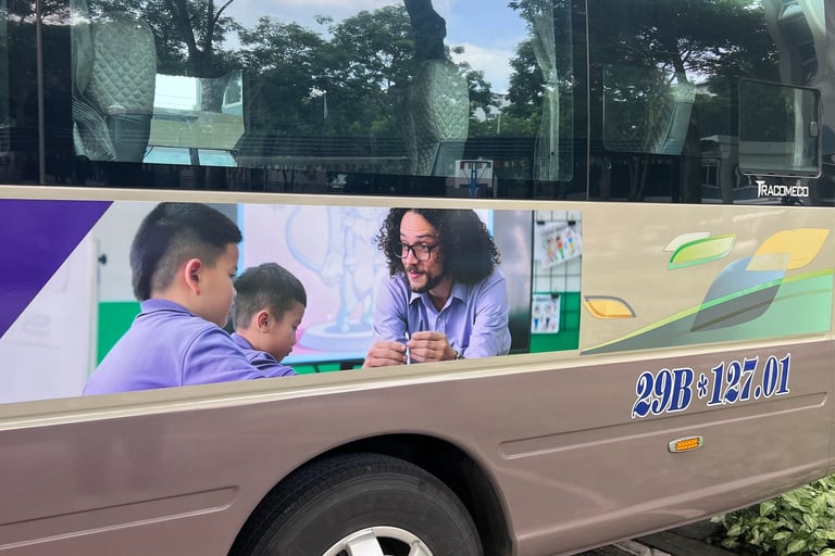 A bus with a advertisement of a school. The advertisement has a male teacher teaching students.