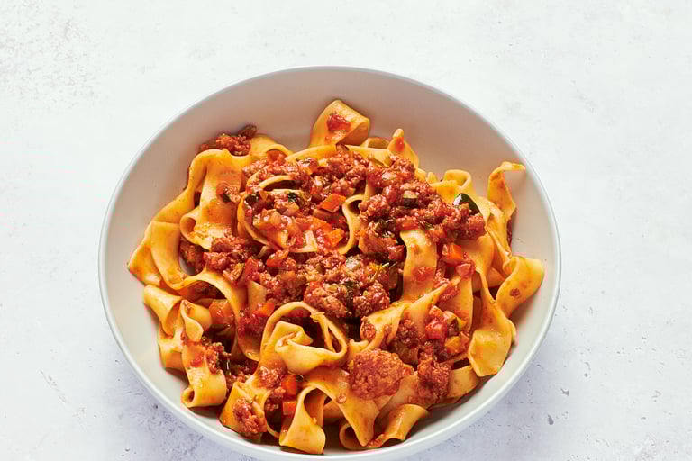 a bowl of pasta with vegan protein mince meat and vegetables