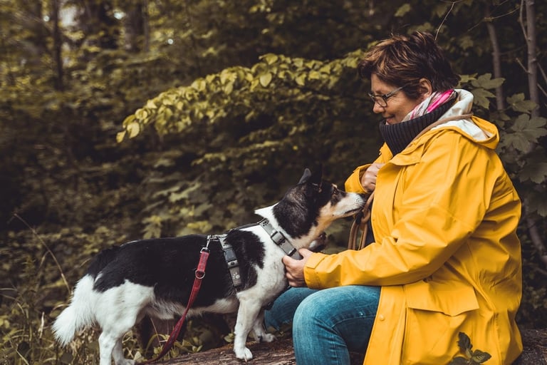Marion Lindhof im Wald mit Pensionshund Trapper., der Nähe sucht.