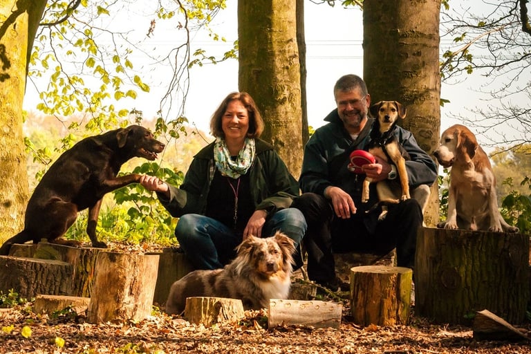 Marion und Martin Lindhof relaxed im Wald mit vier Hunden.