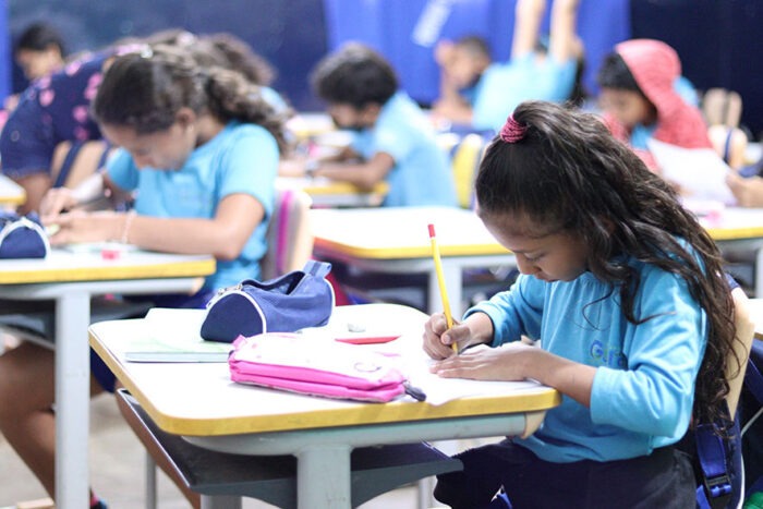 imagem mostra uma menina em sala de aula estudando