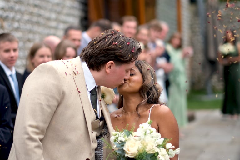 A bridge and groom kissing with confetti being thrown