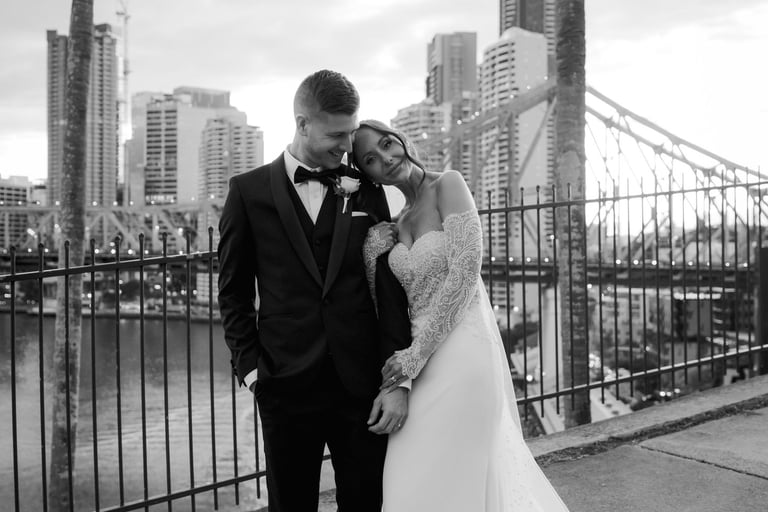 a bride and groom kissing in front of a bridge