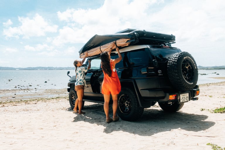 Two women setting up an awning attached to their Toyota FJ Cruiser on the beach in Okinawa. | Evertrail Okinawa