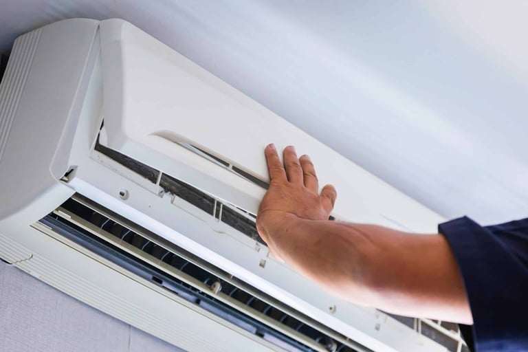 a person holding a hand over a white air conditioner