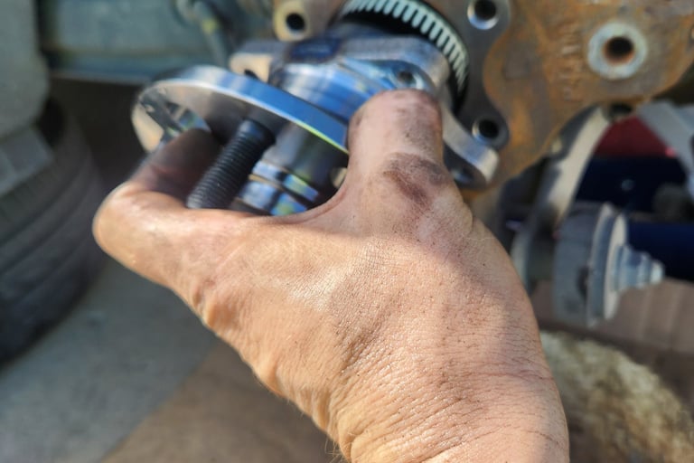 Fast T's Technicians hand lifting a wheel bearing assembly into place for installation 