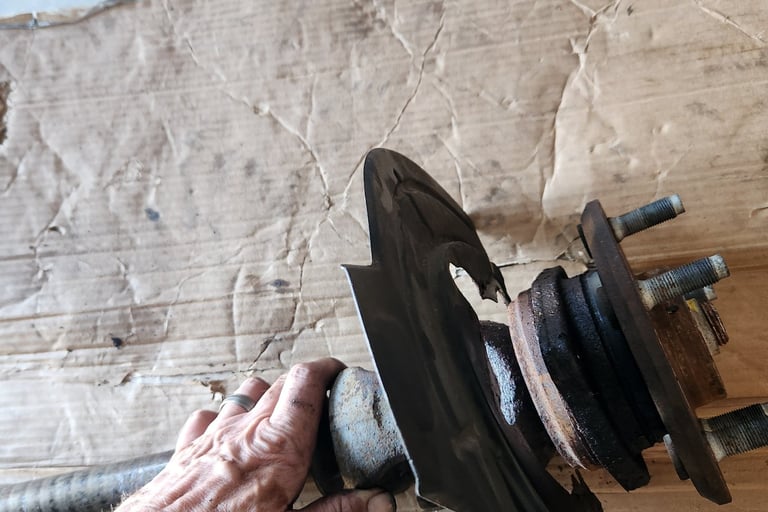 Fast T's Master Mechanic removing an axle from a 2014 Jeep Wrangler Unlimited Sport and placing it on a piece of cardboard on