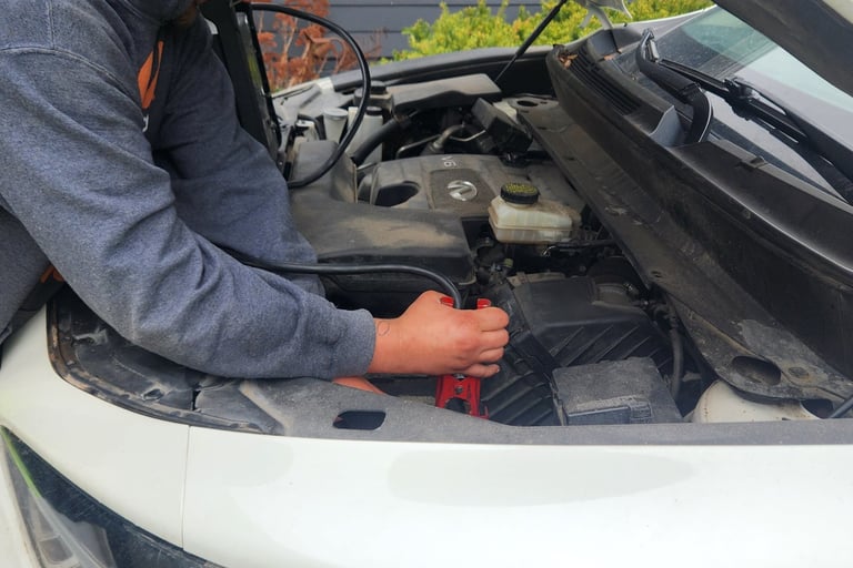 Auto Technician Dontez using a portable power unit to perform a battery jump start service for a customers vehicle in Central