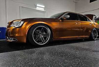 Metallic bronze vinyl wrap on a Chrysler 300 sedan with dark wheels, expertly installed in the shop.