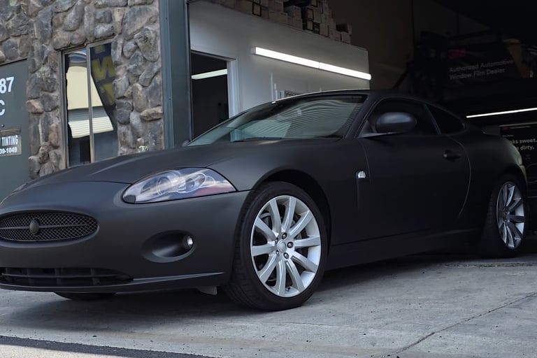 Matte black vinyl wrap on a Jaguar coupe , expertly installed in the shop.