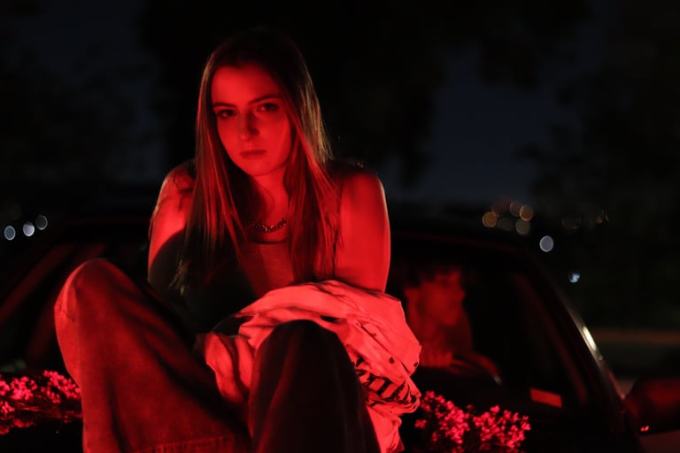 Photo of Audra Baruch on top of a car underneath a red light