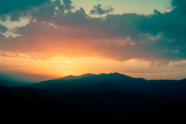 a sunset over a mountain range with a view of the sun setting