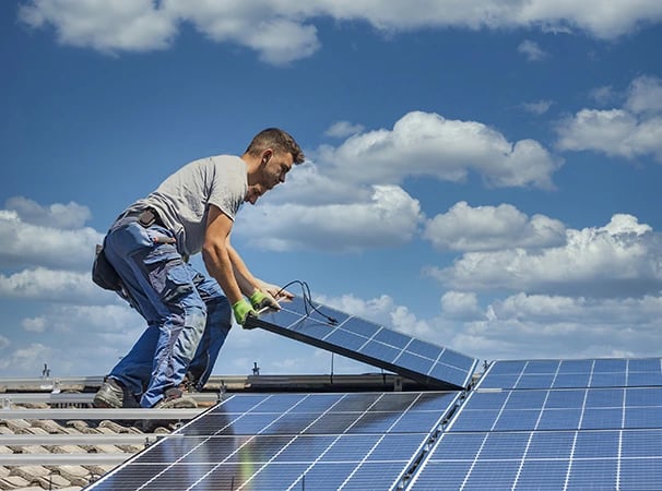 Professional technician installing solar panels on a residential rooftop for renewable energy.