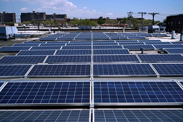 A commercial rooftop solar panel installation under a clear blue sky in an urban city environment.