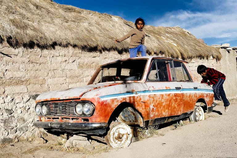 Des enfants jouent sur l'épave d'une voiture dans le salar d'Uyuni en Bolivie