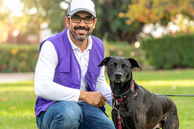 a poof pet waste removal technician wearing the uniform- purple vest and hat, with a dog