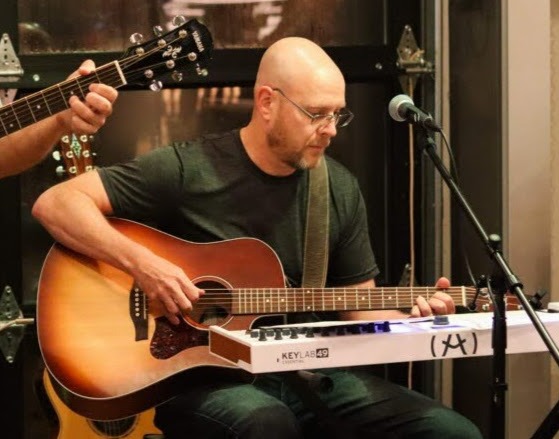 William Finn of Finn's Echo playing in front of a live audience at an open-mic night event.