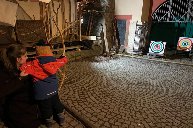 Medieval christmas market, girl teaching child to draw a bow
