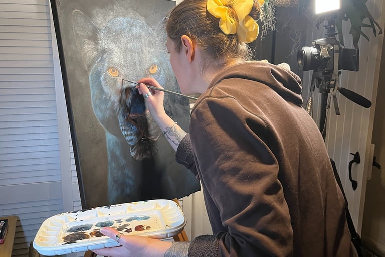 Artist painting a realistic black panther portrait on canvas with fine details.